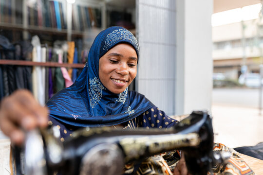 African dressmaker woman working with sewing machine at outdoor atelier