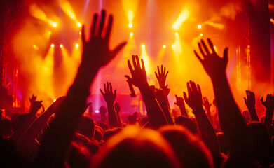 A lively concert with a vibrant crowd raising their hands under colorful stage lights and dynamic atmosphere.

