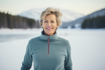 Obraz premium Portrait of a jovial woman in her 50s donning a classy polo shirt isolated in backdrop of a frozen winter lake
