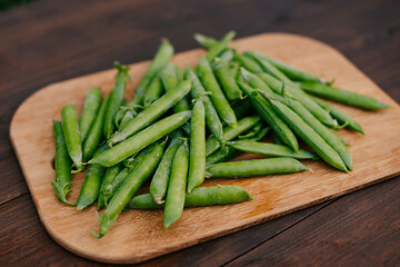 Fresh green peas in bowl on wooden background. wooden table background
