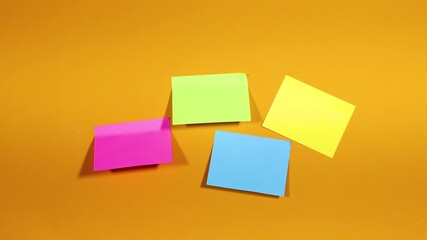 A woman hand sticks a colorful  pieces of paper for notes on a yellow surface