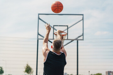 A basketball player shooting the ball towards the hoop, captured from behind, mid-air shot.