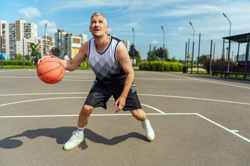 Naklejka premium A focused basketball player in mid-dribble, ready to make a move on the outdoor court.