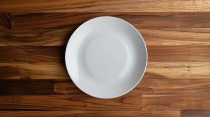 Top view of a pristine white plate on a natural wooden surface, perfect for showcasing dishes or adding text.