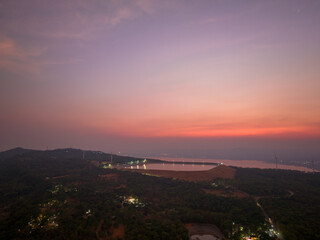 Fototapeta premium A serene aerial view of a reservoir reflecting the warm colors of the sunset. wind turbines in the distance. The scene captures the tranquility of nature and the harmony of renewable energy.