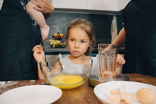 A Young Child Actively Assisting in the Family Kitchen Using Eggs and Various Cooking Tools. Happy family enjoys moments of cooking at home.