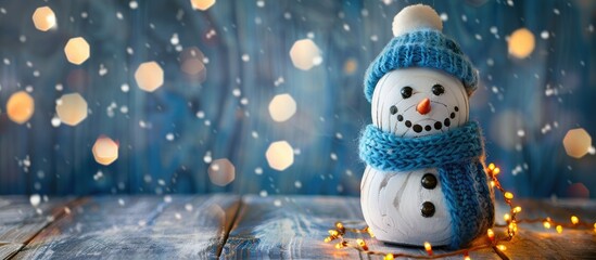 Snowman made of wood adorned with a blue hat and twinkling fairy lights against a copy space image
