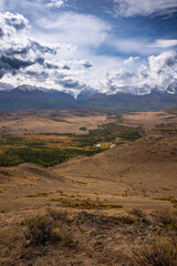 Breathtaking view of a vast mountain valley with snowcapped peaks under a dramatic sky, showcasing nature grandeur. 