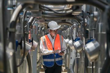 Engineers inspect gas and water pipes for power and cooling in industrial and building systems. workers in safety gear work seriously in oil and gas refining plant with pipes connecting to machinery.