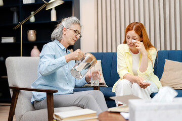 Psychotherapist offering glass of water to crying patient during therapy session