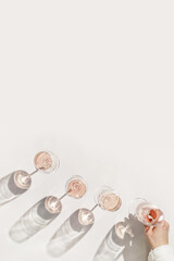 Rose wine glasses Minimal style above view. Aesthetic still life photo, woman's hand take wineglass, sun shadow, Concept of taste, alcohol, wine degustation, home ralahation. Flat lay copyspace