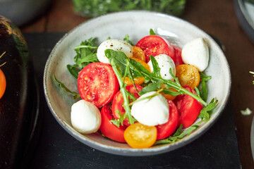 top view of ceramic bowl with tomato and cheese salad with herbs 