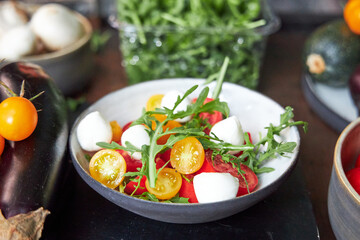 top view of ceramic bowl with tomato and cheese salad with herbs 