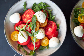 top view of ceramic bowl with tomato and cheese salad with herbs 