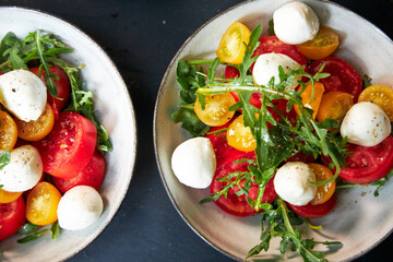 top view of ceramic bowl with tomato and cheese salad with herbs 