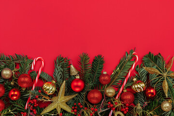 festive Christmas border made of green pine branches, red and gold ornaments, and candy canes, set against a bright red background with ample space for text or other design elements