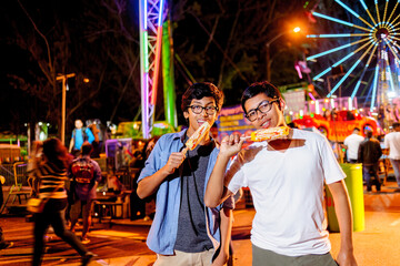 Portrait of two young people in an amusement park at night.