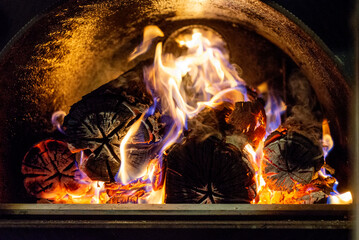 Burning firewood in fire-box of boiler in country cottage.