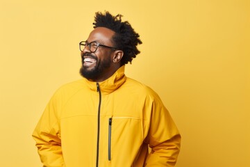 Fototapeta premium Portrait of a glad afro-american man in his 40s wearing a windproof softshell on pastel yellow background
