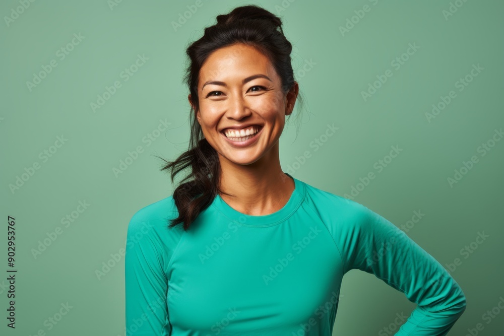 Wall mural Portrait of a grinning asian woman in her 30s sporting a breathable mesh jersey on pastel green background