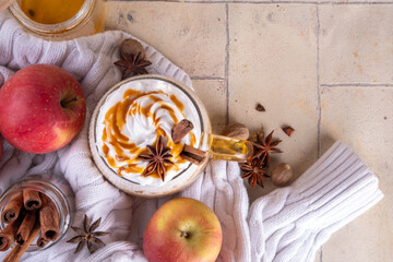 Apple pie spices latte drink, cosy autumn warm coffee beverage with apple pie syrup and spices, with fresh red apples, cinnamon, anise, copy space