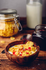 Breakfast with corn flakes, milk and berry syrup