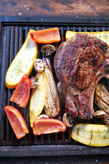 two steaks of meat and vegetables grilled on the grill table