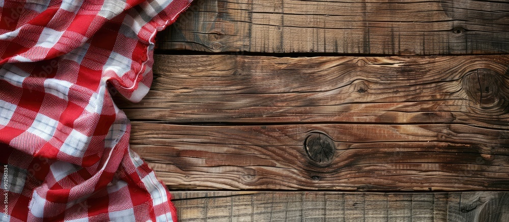 Poster red checkered napkin or tablecloth on raw wooden table showing planks and texture with available cop