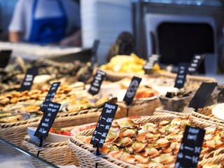 A close-up view of a seafood stall at a traditional fish market, showcasing a variety of fresh shellfish including zamburiñas and other marine delicacies