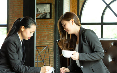 Young business females lesbian LGBTQ couple working together, doing homework, preparing for financial project using laptop. Female colleagues falling in love. LGBTQ project.
