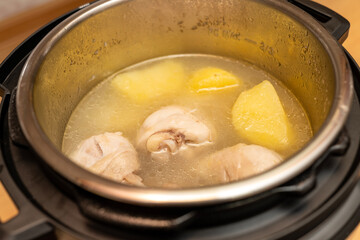 Pressure Cooker potato, meat, chicken  food during cooking. Cooking potatos in boiling water in saucepan electric multicooker pot. smart and healthy cooking in the modern kitchen by multi cooker.
