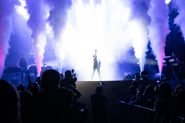 Blurred background rock concert with light background, concert in hall at night. people enjoying music performance in hall. musicians on the stage and spotlights with colored rays. concert and crowd.