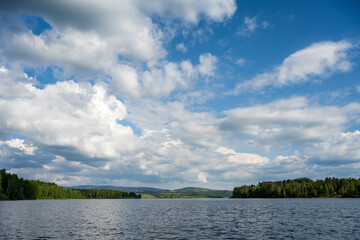 White puffy clouds and blue sky above Vlasina Lake. White cumulus clouds and a blue sky with sun rays. Beautiful semi-artificial lake in Southeast Serbia. 