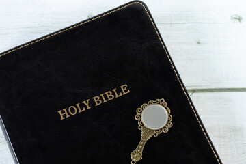 Holy bible book and antique mirror on wooden table. Top view. Biblical concept of Christian...