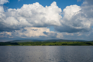 White puffy clouds and blue sky above Vlasina Lake. White cumulus clouds and a blue sky with sun...