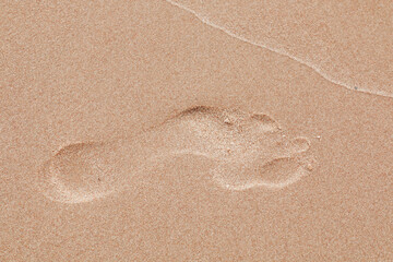 Footprints on brown sand from a man's foot.