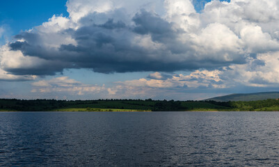 White puffy clouds and blue sky above Vlasina Lake. White cumulus clouds and a blue sky with sun rays. Beautiful semi-artificial lake in Southeast Serbia. 