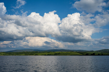 White puffy clouds and blue sky above Vlasina Lake. White cumulus clouds and a blue sky with sun...