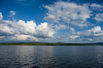 White puffy clouds and blue sky above Vlasina Lake. White cumulus clouds and a blue sky with sun...