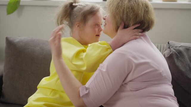 Child with Down syndrome and mother share loving embrace at home. Interaction illustrates crucial role of family in early intervention and education. Concept: early support, parental involvement