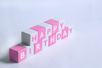 Happy birthday text written on pink white cubes with white background
