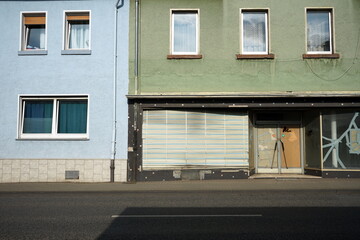 Leerstehendes Gesch&auml;ft mit alter Jalousie, Notverglasung und zersprungenem Schaufenster mit Klebeband bei Sonnenschein in der Krofdorfer Stra&szlig;e in Gie&szlig;en in Hessen