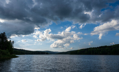 White puffy clouds and blue sky above Vlasina Lake. White cumulus clouds and a blue sky with sun rays. Beautiful semi-artificial lake in Southeast Serbia. 