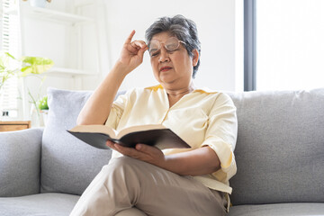 Presbyopia, Hyperopia mature, aged asian woman having vision problem trying to stare read text on a...