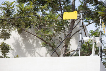 A yellow sign is hanging from a wire above a tree