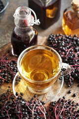 A cup of tea with black elderberry syrup on a table