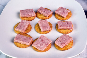 sliced spam  resting on whole wheat crackers