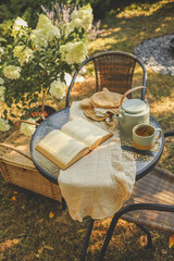 Summer morning in the garden. A book, a wicker basket, a hat and tea