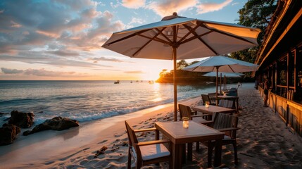 Fototapeta premium Scenic beachside dining area with wooden tables and chairs under large umbrellas, overlooking the sea at sunrise, creating a serene and inviting atmosphere.