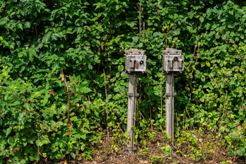 Two old rusty electrical switches with a button for moving railway switches on a background of green foliage